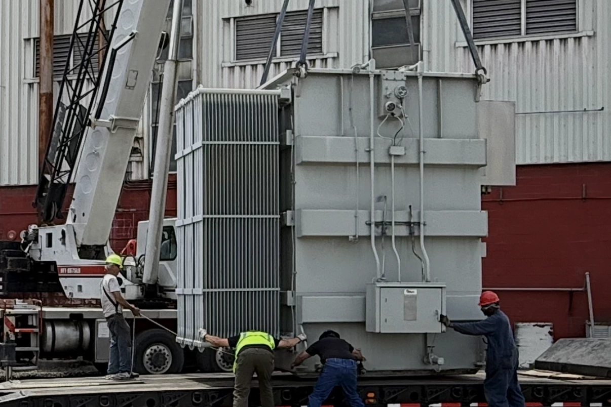 Our crew rigging a power transformer onto a lowboy trailer under a crane