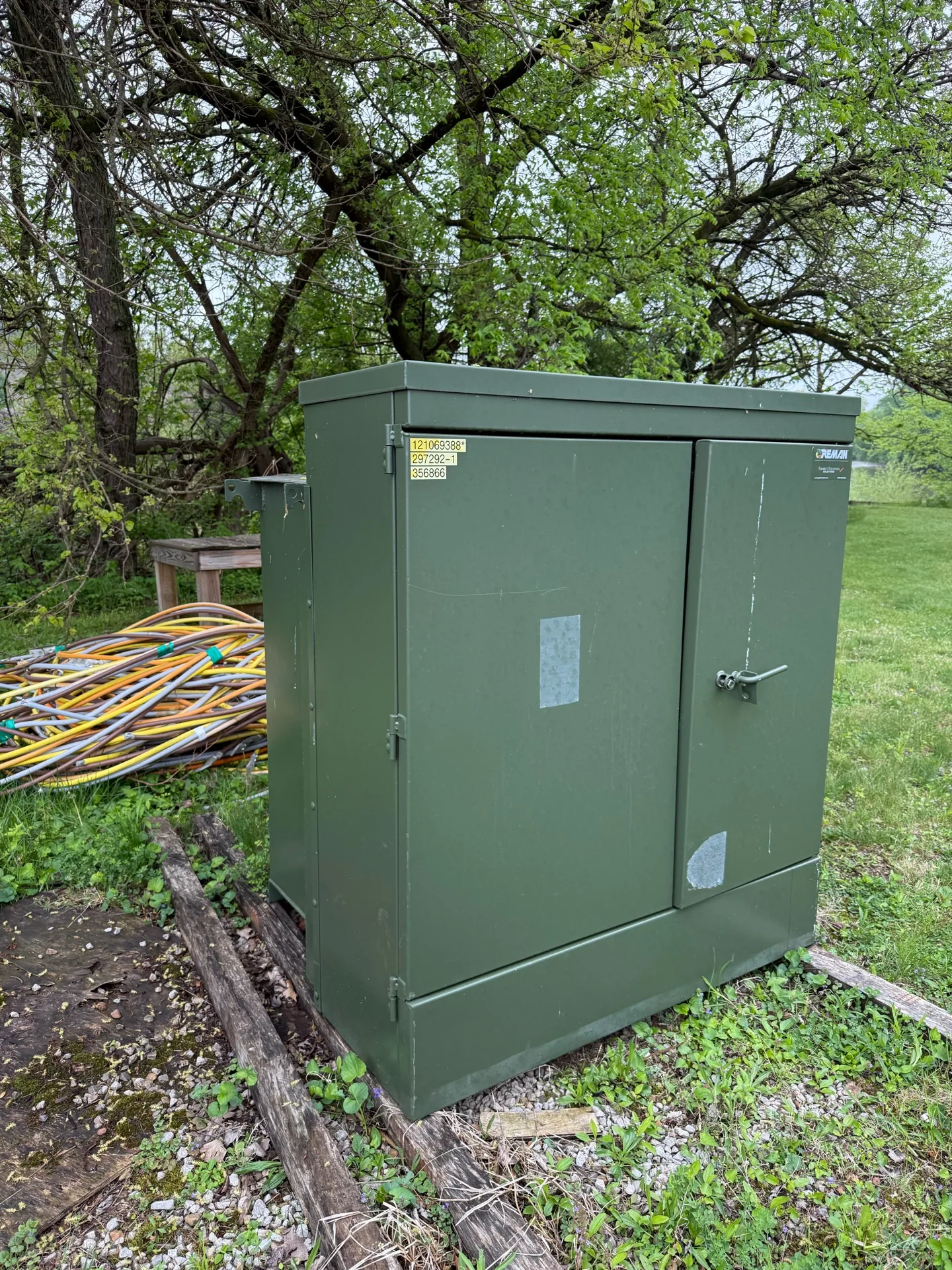 Green pad-mount transformer set on a concrete pad